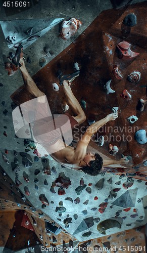 Image of Free climber young man climbing artificial boulder indoors