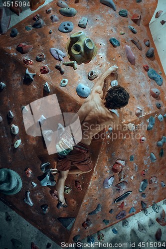 Image of Free climber young man climbing artificial boulder indoors