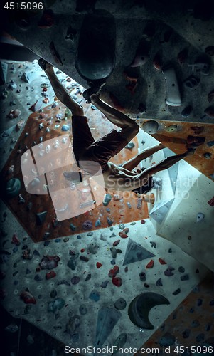 Image of Free climber young man climbing artificial boulder indoors