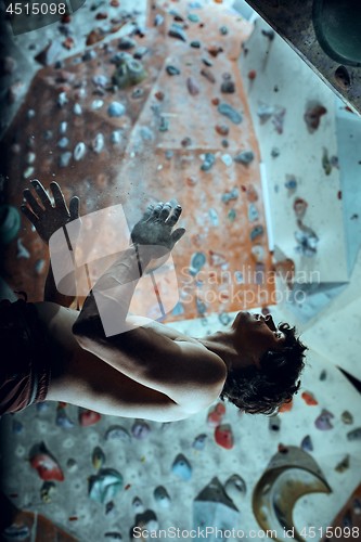 Image of Free climber young man climbing artificial boulder indoors