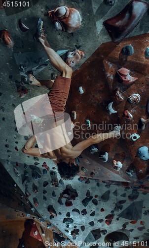 Image of Free climber young man climbing artificial boulder indoors