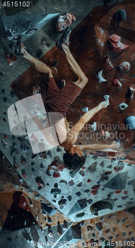 Image of Free climber young man climbing artificial boulder indoors