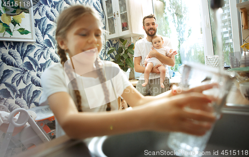 Image of The happy smiling caucasian family in the kitchen preparing breakfast