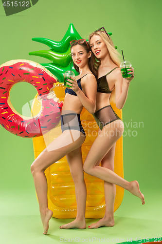 Image of Cute girls in swimsuits posing at studio. Summer portrait caucasian teenagers on green background.