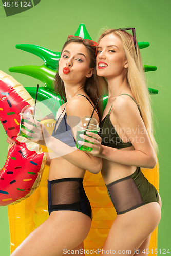 Image of Cute girls in swimsuits posing at studio. Summer portrait caucasian teenagers on green background.