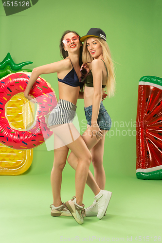 Image of Cute girls in swimsuits posing at studio. Summer portrait caucasian teenagers on green background.