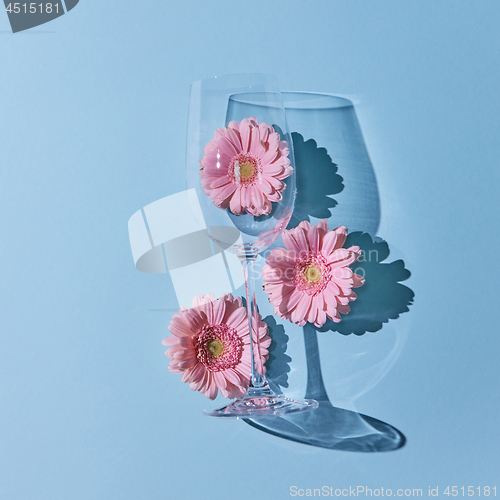 Image of Glass of wine with pink gerberas on a blue background