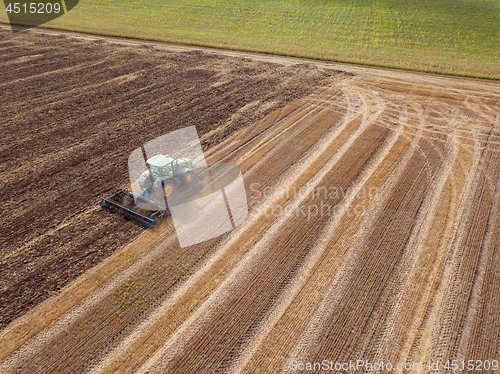 Image of An endless agricultural field after harvesting with tractor on it . Cultivation of the soil by a tractor for sowing works.