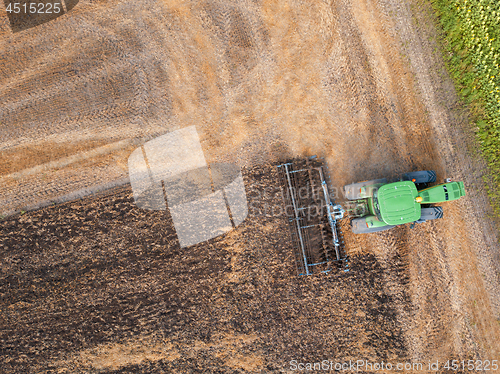 Image of Panoramic view of the green tractor plows the field, preparing the soil for agricultural work. Top view.