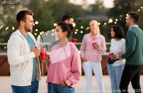 Image of friends with drinks in party cups at rooftop