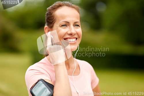 Image of woman with earphones listening to music at park