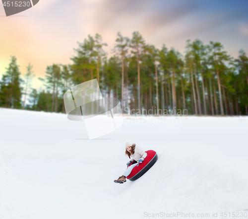 Image of happy teenage girl sliding down hill on snow tube