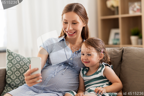 Image of pregnant mother and daughter with smartphone