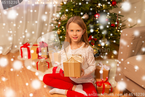 Image of smiling girl with christmas gift at home