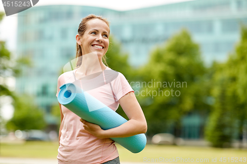 Image of happy smiling woman with exercise mat at city park