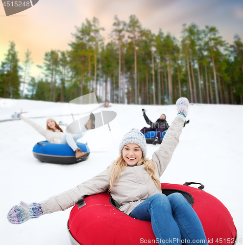 Image of happy friends sliding down hill on snow tubes