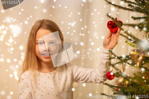 Image of happy girl in red dress decorating christmas tree