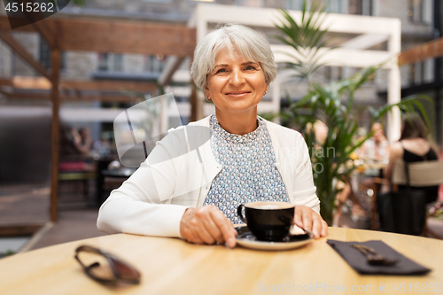 Image of senior woman with coffee at street cafe