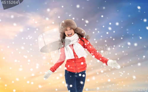 Image of happy woman in winter fur hat over sky and snow