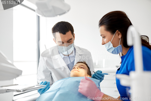 Image of dentist checking for kid teeth at dental clinic