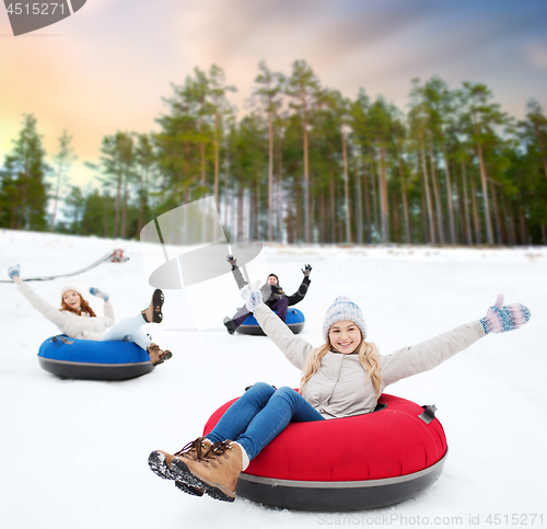 Image of happy friends sliding down hill on snow tubes