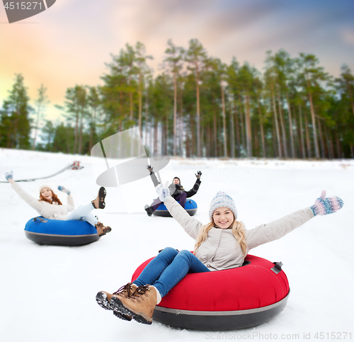 Image of happy friends sliding down hill on snow tubes