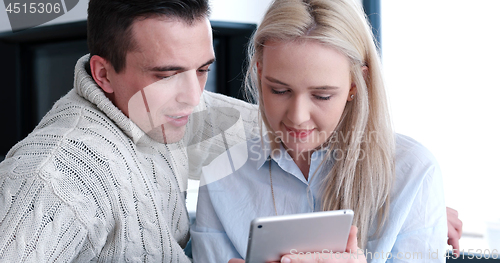 Image of Young Couple using digital tablet on the floor