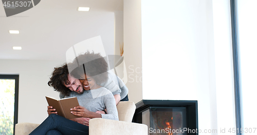 Image of multiethnic couple hugging in front of fireplace