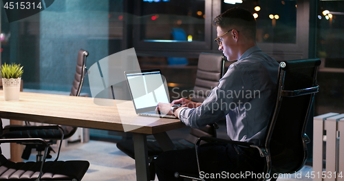 Image of man working on laptop in dark office