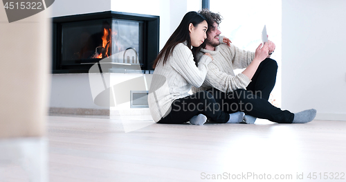 Image of Young Couple using digital tablet on the floor