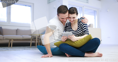 Image of Young Couple using digital tablet on the floor