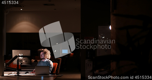 Image of man working on computer in dark office