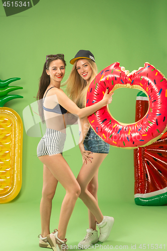 Image of Cute girls in swimsuits posing at studio. Summer portrait caucasian teenagers on green background.