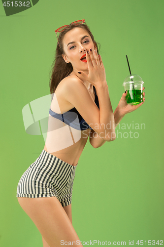 Image of Cute girl in swimsuit posing at studio. Summer portrait caucasian teenager on green background.