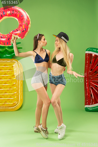 Image of Cute girls in swimsuits posing at studio. Summer portrait caucasian teenagers on green background.