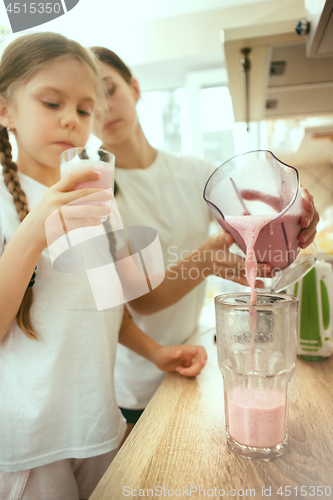 Image of The happy smiling caucasian family in the kitchen preparing breakfast