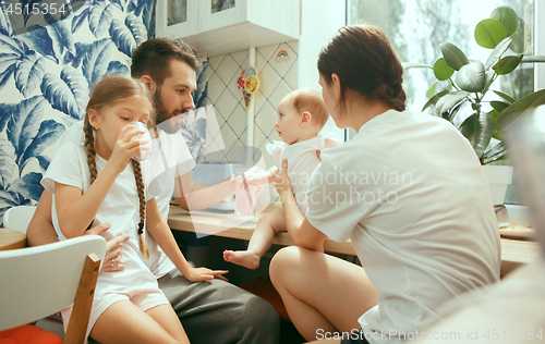 Image of The happy smiling caucasian family in the kitchen preparing breakfast