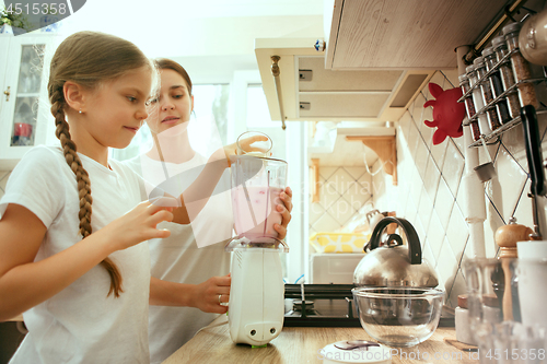 Image of The happy smiling caucasian family in the kitchen preparing breakfast