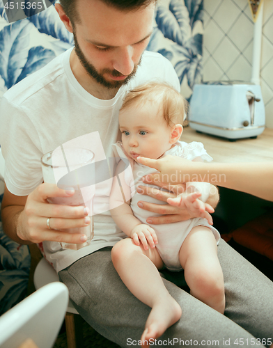 Image of The happy smiling caucasian family in the kitchen preparing breakfast