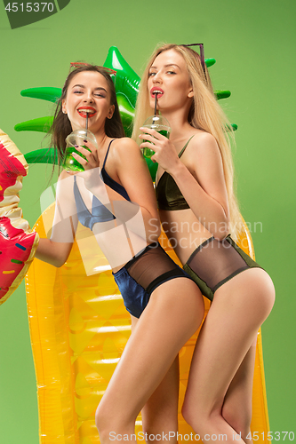 Image of Cute girls in swimsuits posing at studio. Summer portrait caucasian teenagers on green background.