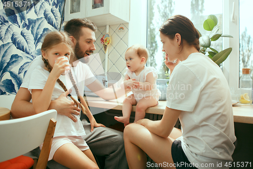 Image of The happy smiling caucasian family in the kitchen preparing breakfast