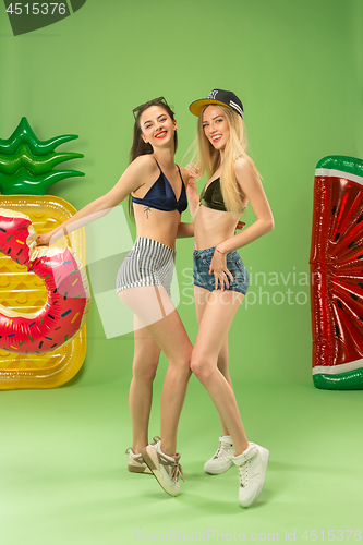 Image of Cute girls in swimsuits posing at studio. Summer portrait caucasian teenagers on green background.