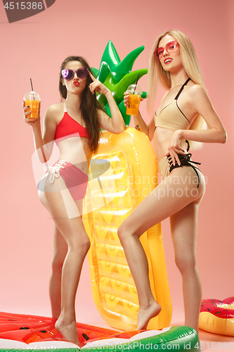 Image of Cute girls in swimsuits posing at studio. Summer portrait caucasian teenagers on pink background.