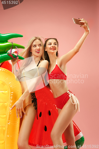 Image of Cute girls in swimsuits posing at studio. Summer portrait caucasian teenagers on pink background.