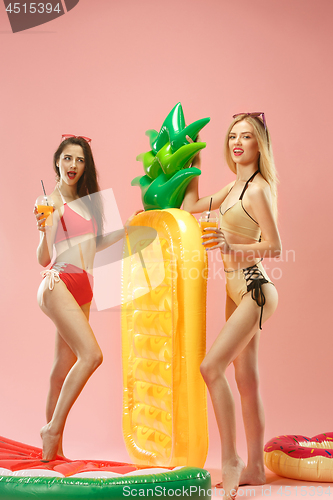 Image of Cute girls in swimsuits posing at studio. Summer portrait caucasian teenagers on pink background.