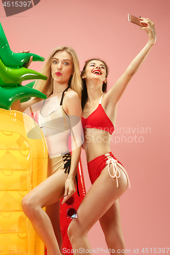 Image of Cute girls in swimsuits posing at studio. Summer portrait caucasian teenagers on pink background.