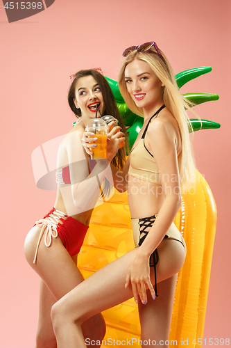 Image of Cute girls in swimsuits posing at studio. Summer portrait caucasian teenagers on pink background.