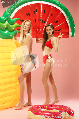 Image of Cute girls in swimsuits posing at studio. Summer portrait caucasian teenagers on pink background.