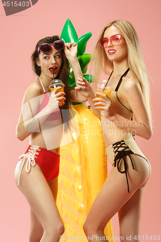 Image of Cute girls in swimsuits posing at studio. Summer portrait caucasian teenagers on pink background.