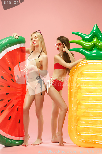 Image of Cute girls in swimsuits posing at studio. Summer portrait caucasian teenagers on pink background.